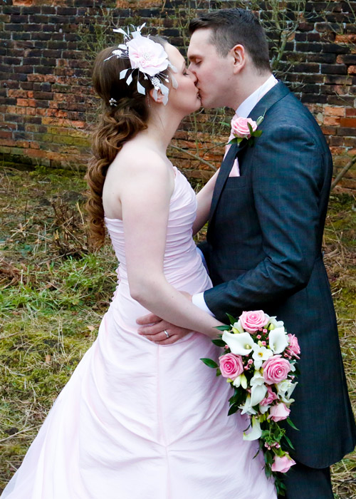 bride in pink wedding dress kissed groom with blue suit
