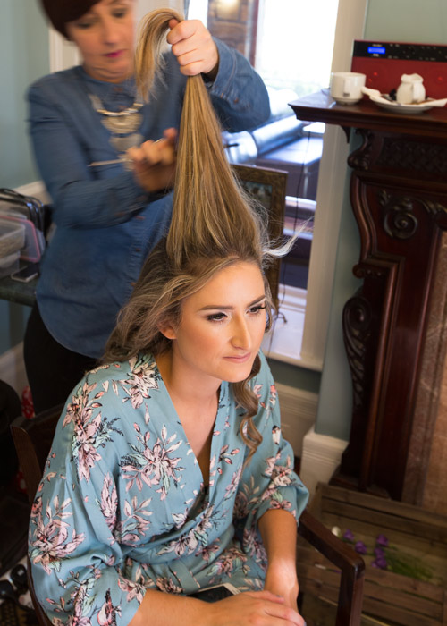 bridesmaid in blue robe having hair done on the morning of the wedding