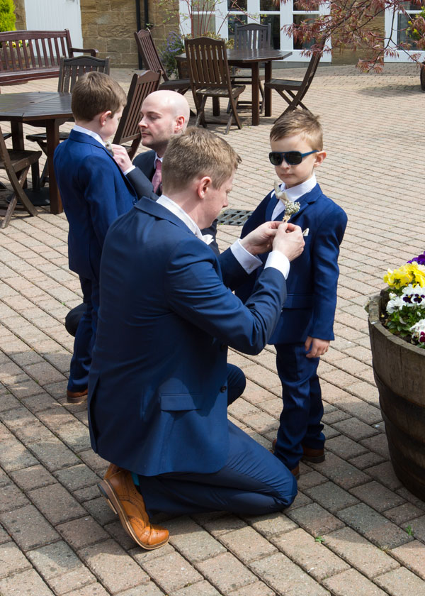 groom in blue suit putting buttonhold onto pageboy the stables high melton doncaster