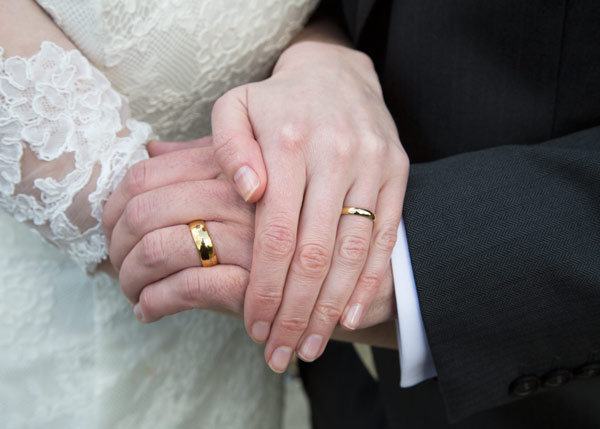 golden wedding rings on newlyweds hands close up
