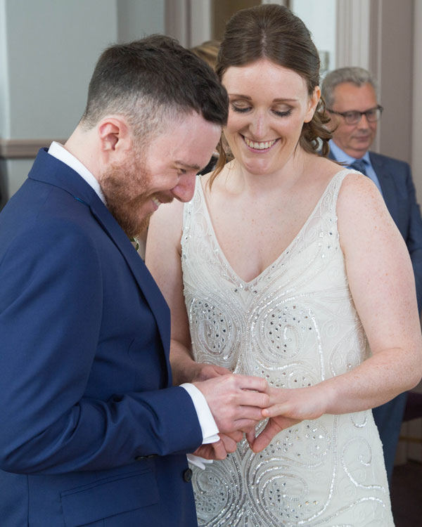 bride and groom exchanging rings during Leeds town hall wedding ceremony photographer