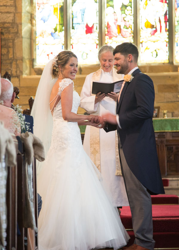 Bride and Groom laughing and looking at the guests during their wedding ceremony at Felkirk Church Shafton