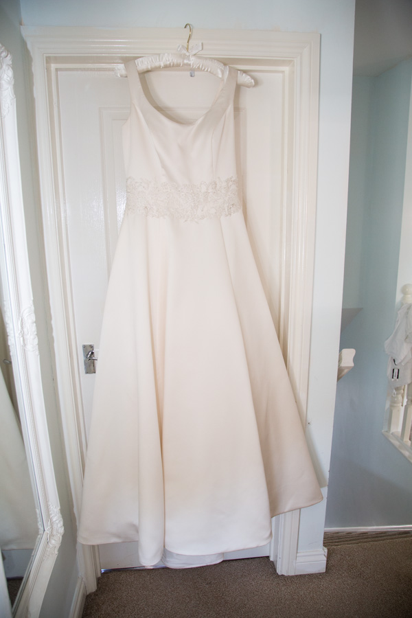 Bride's dress hanging on a white door
