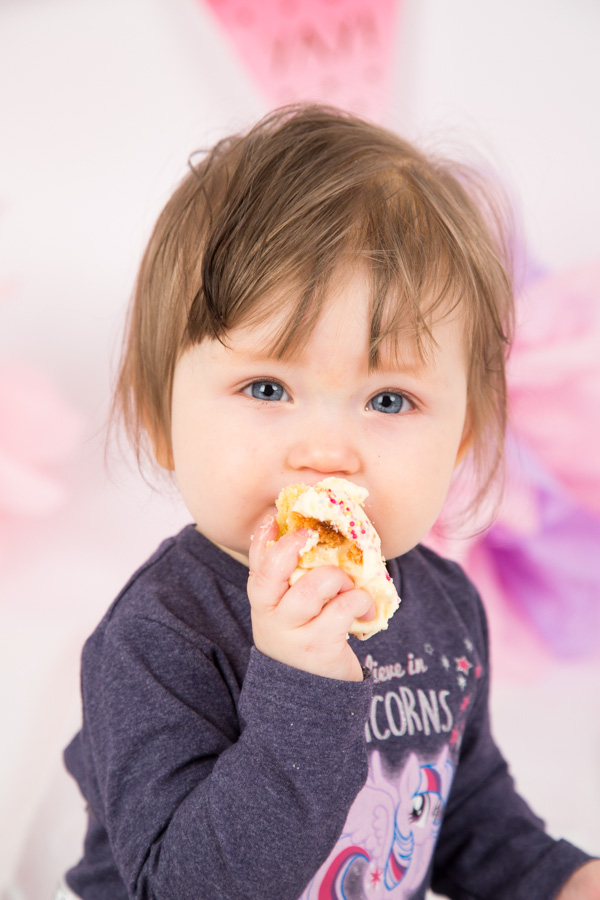 Baby girl eating cake during her cake smash session
