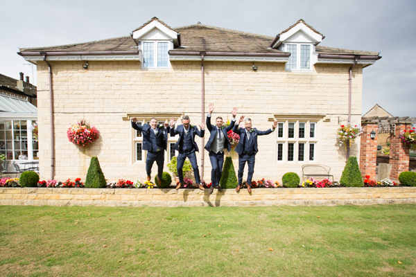 Groom and Groomsmen jumping off wall at Rogerthorpe Manor Wedding