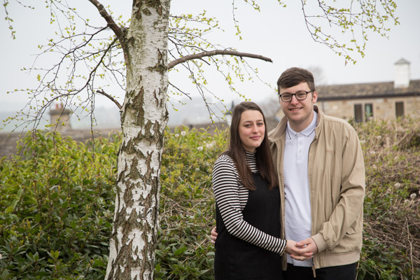 Couple next to a tree with Tankersley Manor in the background at pre-wedding session