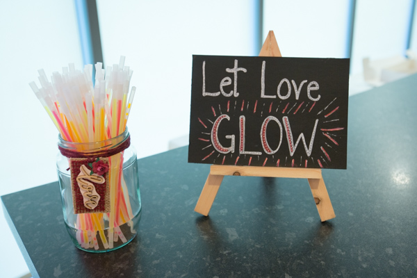 Let Love Glow sign next to a glass of glow sticks at Ibis Styles Hotel Barnsley wedding