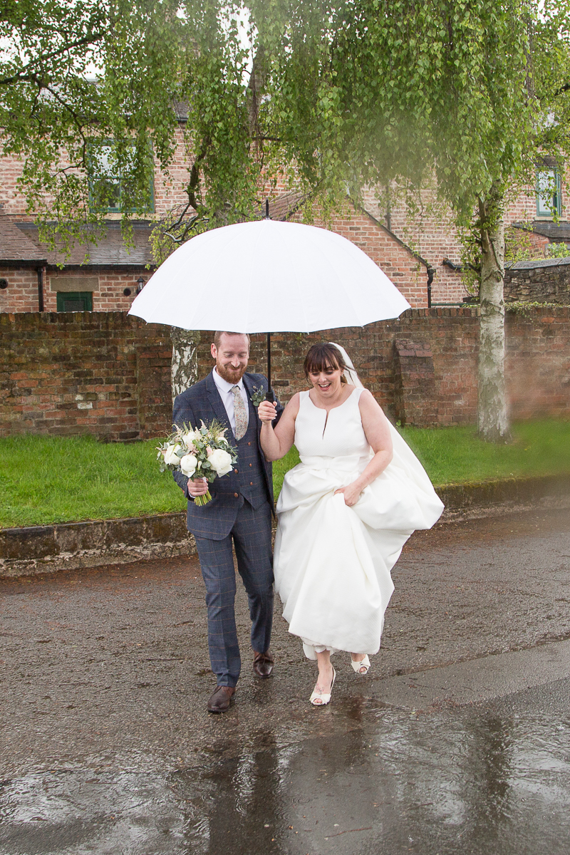 Bride and groom walking over puddles at Elsecar Heritage Centre on their wedding day