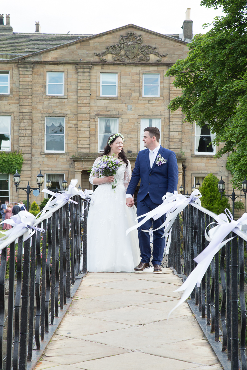 Bride and groom walking across the bridge at Waterton Park Hotel