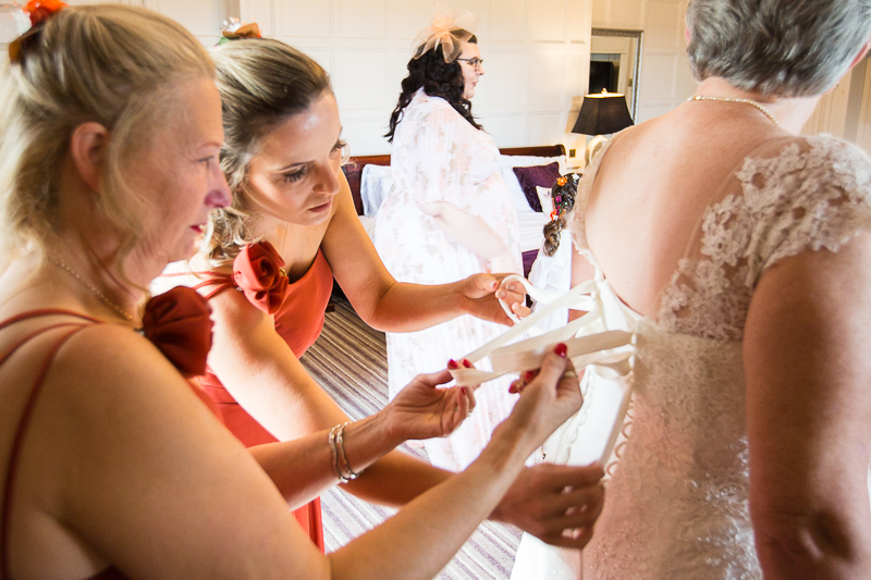 Bridesmaids fastening the brides corset dress in the Bridal Suite at Wortley Hall Hotel Sheffield