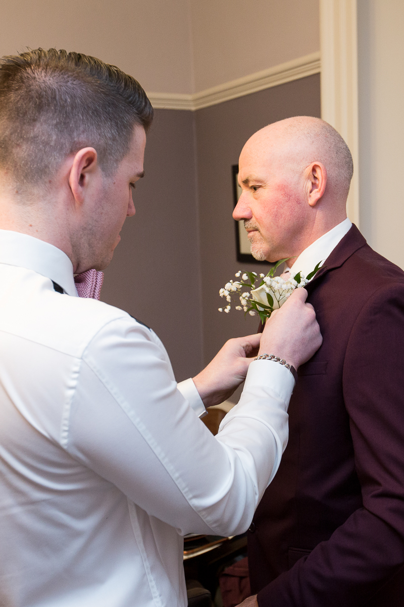 Groom putting on his fathers buttonhole at Cubley Hall