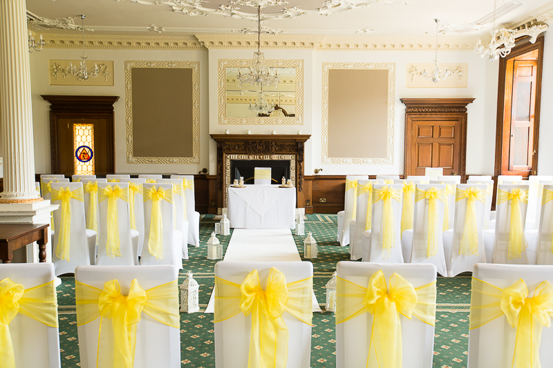 The wedding ceremony room at Wortley Hall Hotel Sheffield decorated with yellow chair backs and white aisle runner