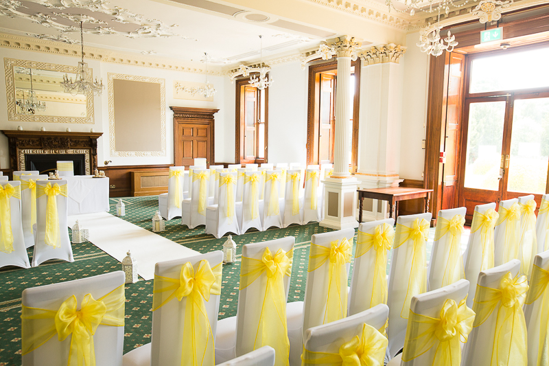 The wedding ceremony room at Wortley Hall Hotel Sheffield decorated with yellow chair backs and white aisle runner