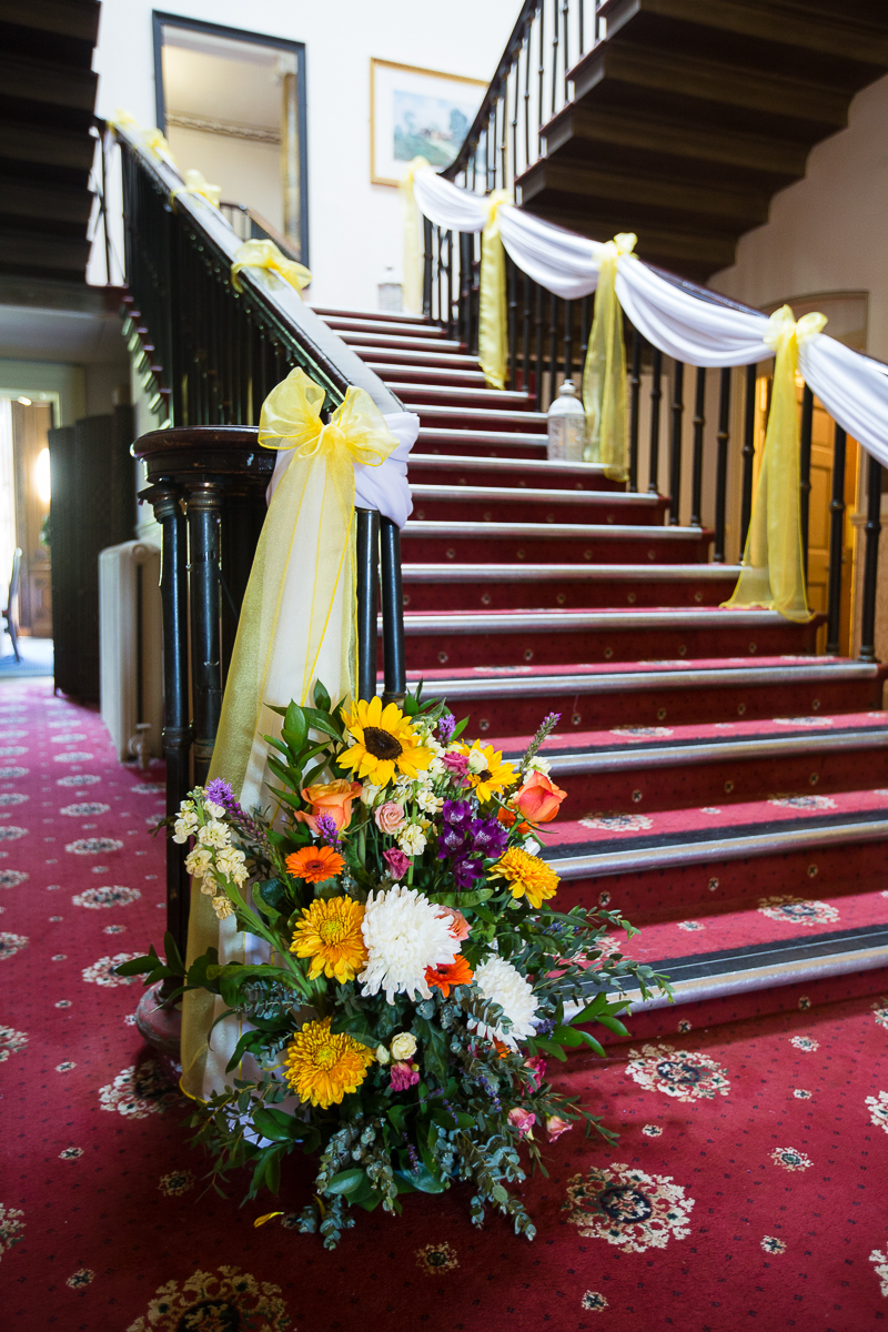 Staircase at Wortley Hall Hotel Sheffield decorated with yellow and white bows and sashes with bright colour flowers