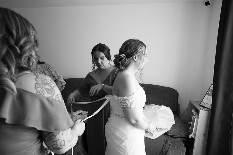 Bridal party fastening brides wedding dress by Sheffield wedding photographer