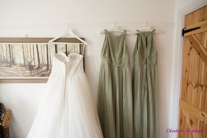 The wedding dress hung with sage green bridesmaid dresses