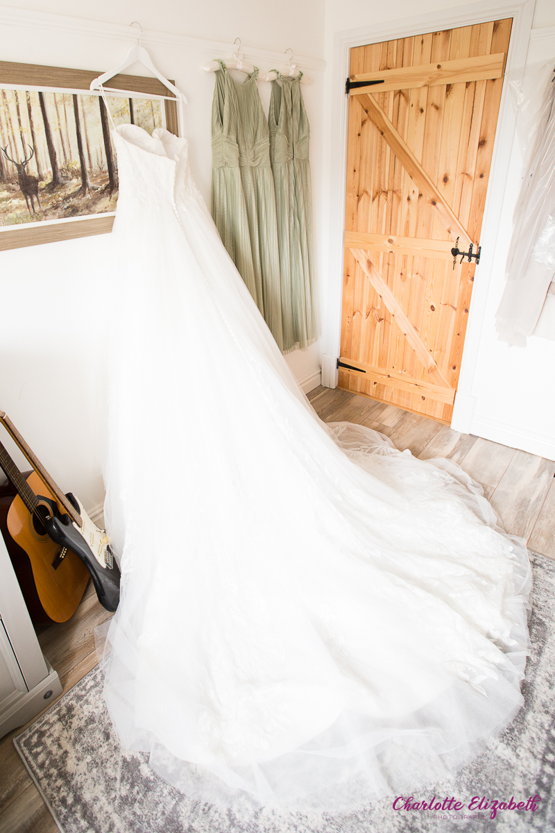 The wedding dress hung with sage green bridesmaid dresses